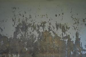 textura do velho muro de concreto cinza para segundo plano. textura áspera na parede cinza forma áspera devido à camada de tinta descascada devido à chuva foto