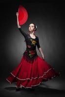 jovem mulher dançando flamenco com ventilador no preto foto
