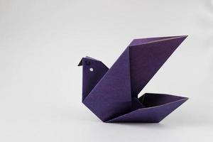 pássaro de origami de papel violeta em fundo branco com espaço de cópia foto