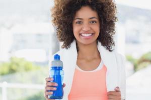 caber jovem fêmea segurando a garrafa de água no ginásio foto