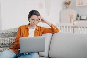 freelancer feminino está cansado. jovem exausta navegando na internet trabalhando durante a quarentena. foto