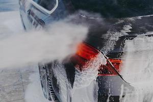 veículo coberto de espuma branca com sabão durante a lavagem regular ao ar livre foto