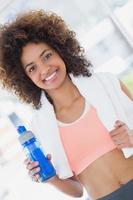 caber jovem fêmea segurando a garrafa de água no ginásio foto