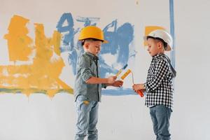 cores azuis e amarelas patrióticas da ucrânia. dois meninos pintando paredes na sala doméstica foto