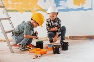 trabalho em progresso. dois meninos pintando paredes na sala doméstica foto