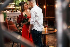 homem dando lindas flores. casal romântico jantando no restaurante foto