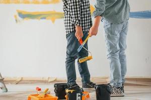 em roupas casuais. dois meninos pintando paredes na sala doméstica foto