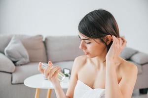 segurando o copo com perfume. jovem está em casa. concepção de beleza foto