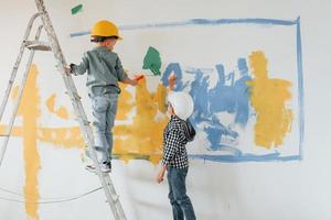 dois meninos pintando paredes na sala doméstica foto