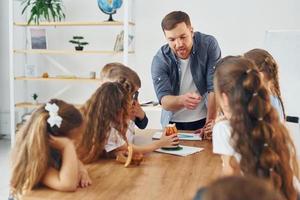 Aula de geografia com globo nas mãos grupo de alunos de crianças