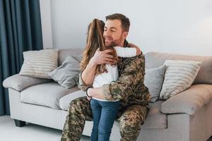 senti sua falta. soldado de uniforme está em casa com sua filha foto