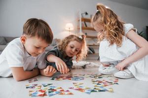 jogando jogo de quebra-cabeça. grupo de crianças está junto em casa durante o dia foto