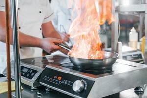 a comida está inflamando e o peso sendo medido. chef profissional preparando comida na cozinha foto