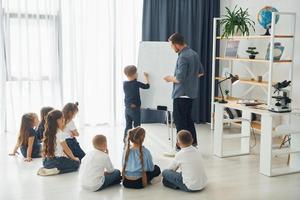 usando quadro branco. grupo de alunos de crianças em sala de aula na escola com professor foto