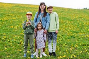 mãe com três filhos em um campo de dente de leão. foto