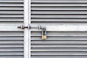 pequeno cadeado pendurado em portas de metal fechadas foto