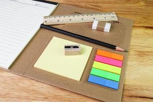 nota de cor de papel e régua de borracha de lápis com livro em woodtable foto