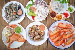 prato de frutos do mar com camarão marisco caranguejo lula berbigão manchado babilônia com molho de frutos do mar pimenta limão servir na mesa de jantar, camarão camarão buffet menu de frutos do mar comida cozida - vista superior foto