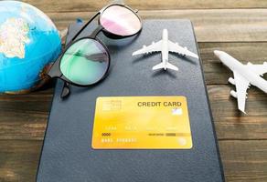 cartão de crédito e modelo de avião na mesa de madeira foto