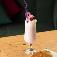 um smoothie de morango saudável em uma caneca com túbulos bebendo ao lado de baklava em uma mesa de madeira foto