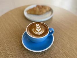 xícara de café quente e croissant na mesa foto