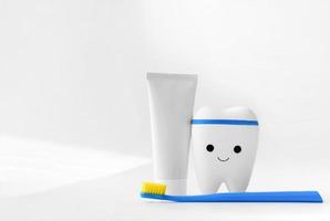 dente de brinquedo, escova de dentes azul e creme dental em fundo branco foto