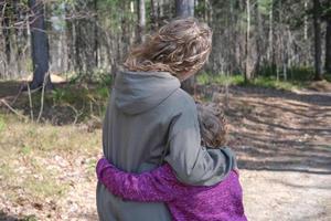 irmãs encaracoladas abraçando enquanto caminhava na floresta. foto