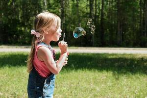 menina bonitinha soprando bolhas de sabão foto