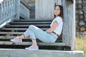 mulher bonita sentada em uma escada da velha casa de madeira abandonada. foto