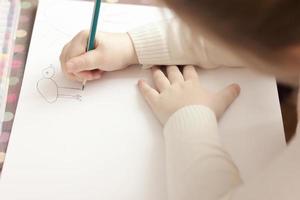 Exibição recortada da garotinha desenhando com um lápis. foto