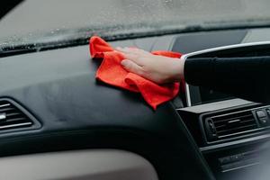 limpador profissional e conceito de limpeza de carro. homem irreconhecível limpa o interior do carro com pano. foco seletivo. lavando o painel do carro com pano foto