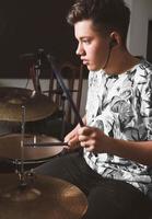 baterista de menino adolescente bonito tocando no ensaio em um estúdio. músico de rock adolescente masculino tocando uma música. conceito de hobby e lazer. tamanho vertical foto