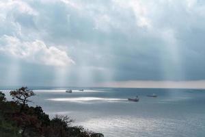 navios de carga fazendo fila em uma baía sob céu dramático. foto