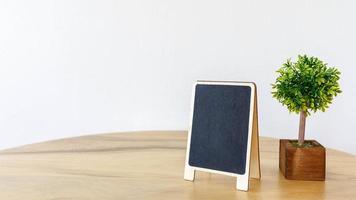 moldura preta em branco simular mini árvore de porta-retrato em pote na mesa de madeira foto