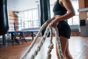 desafio diário. mulher loira esporte tem exercício com cordas no ginásio. mulher forte foto