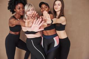 foto focada. grupo de mulheres multiétnicas em pé no estúdio contra fundo marrom