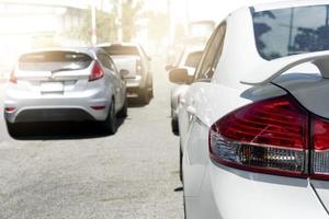 parte traseira do carro branco na estrada de asfalto com luz brilhante. engarrafamentos na cidade durante o dia. fila de muitos carros na frente. foto