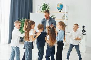 gesto de high fives. grupo de alunos de crianças em sala de aula na escola com professor foto