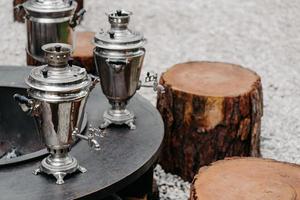 conceito tradicional de beber chá. três antigos samovars de cobre de metal ao ar livre perto de tocos de madeira. estilo rústico. foto