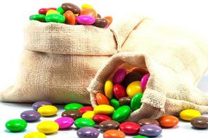 doces de chocolate coloridos em mini saco de saco em fundo branco foto
