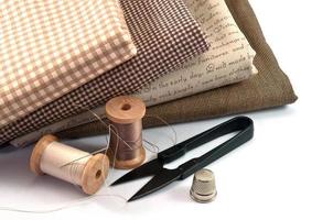 acessório de costura incluindo carretel de linha, agulha, tesoura, dedal e pano em fundo branco foto