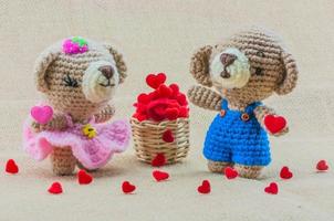 lindo casal bebê ursos boneca de crochê com cesta de corações no fundo de textura de saco foto