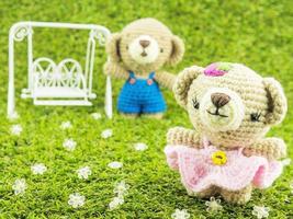 adorável bebê ursos boneca de crochê na grama verde com fundo de balanço, foco no urso da frente foto