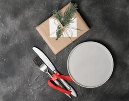 prato vazio com talheres e decoração de natal na mesa cinza. copie o espaço. modelo de configuração de mesa para o menu de ano novo ou natal. maquete do menu do restaurante. vista do topo foto