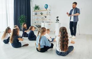 Aula de geografia com globo nas mãos grupo de alunos de crianças