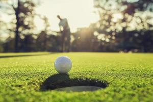 jogador de golfe colocando bola de golfe no buraco foto