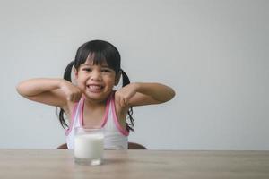 menina asiática está bebendo leite de um copo ela estava muito feliz. foto