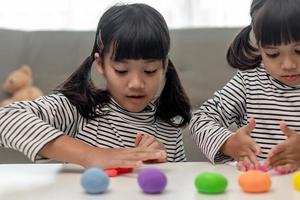 a menina está aprendendo a usar massinha colorida em uma sala bem iluminada foto