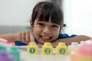 adorável menina jogando blocos de brinquedo em uma sala iluminada foto