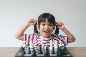 menina asiática jogando xadrez em casa. um jogo de xadrez foto